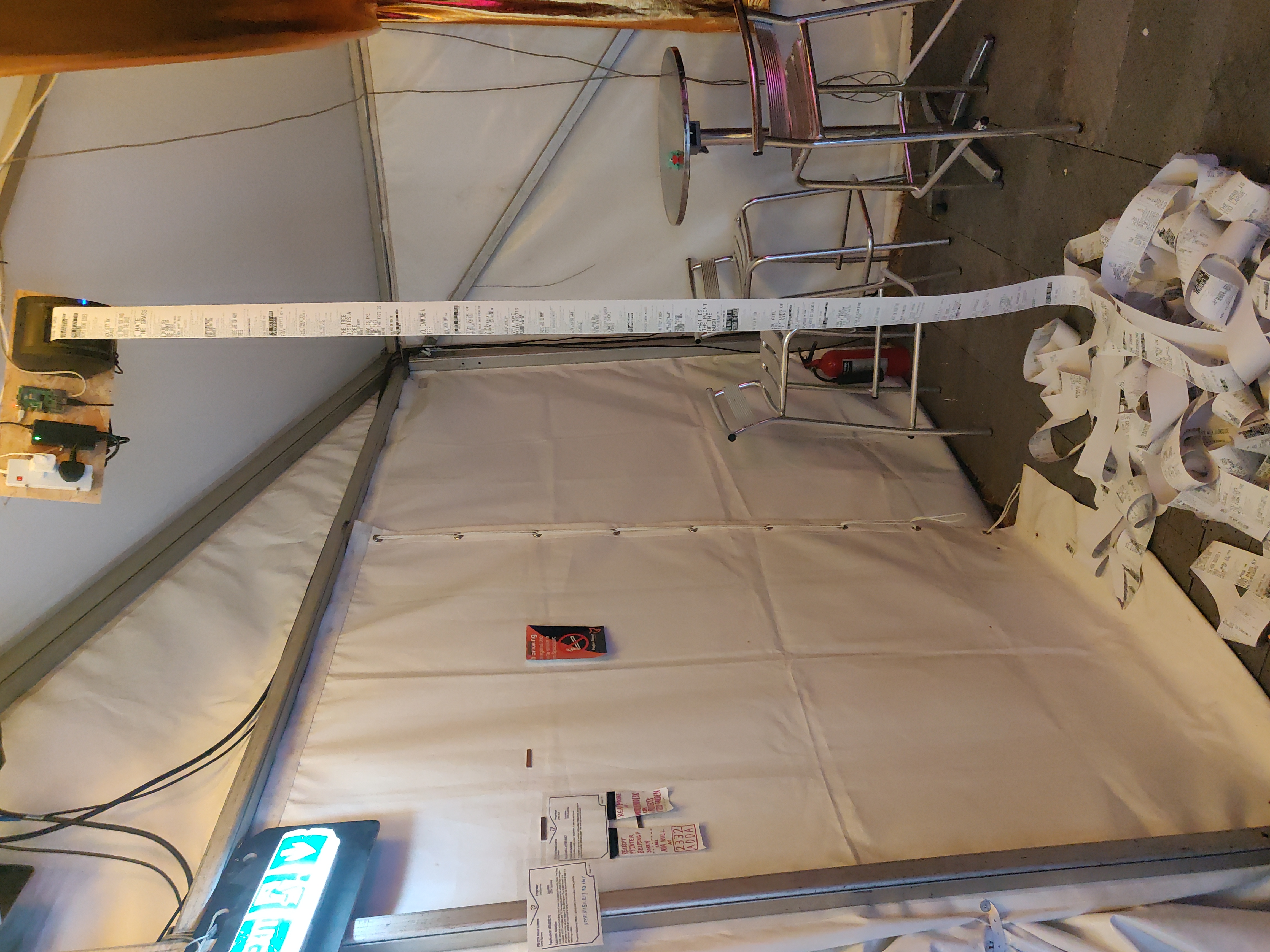A hanging receipt printer, printing receipts into a pile on the floor"